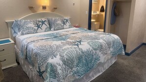A bedroom with a bed, nightstand, and a bathroom visible through an open door. - The Inn at Buzzards Bay (Buzzards Bay)