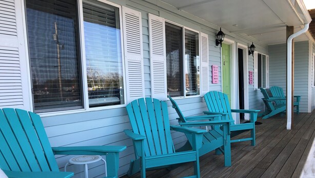 A covered porch with turquoise Adirondack chairs and a wooden table. - The Inn at Buzzards Bay (Buzzards Bay)