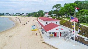 A beachside building with a red roof, a flagpole with multiple flags, and a sign that reads "BAY". - The Inn at Buzzards Bay (Buzzards Bay)