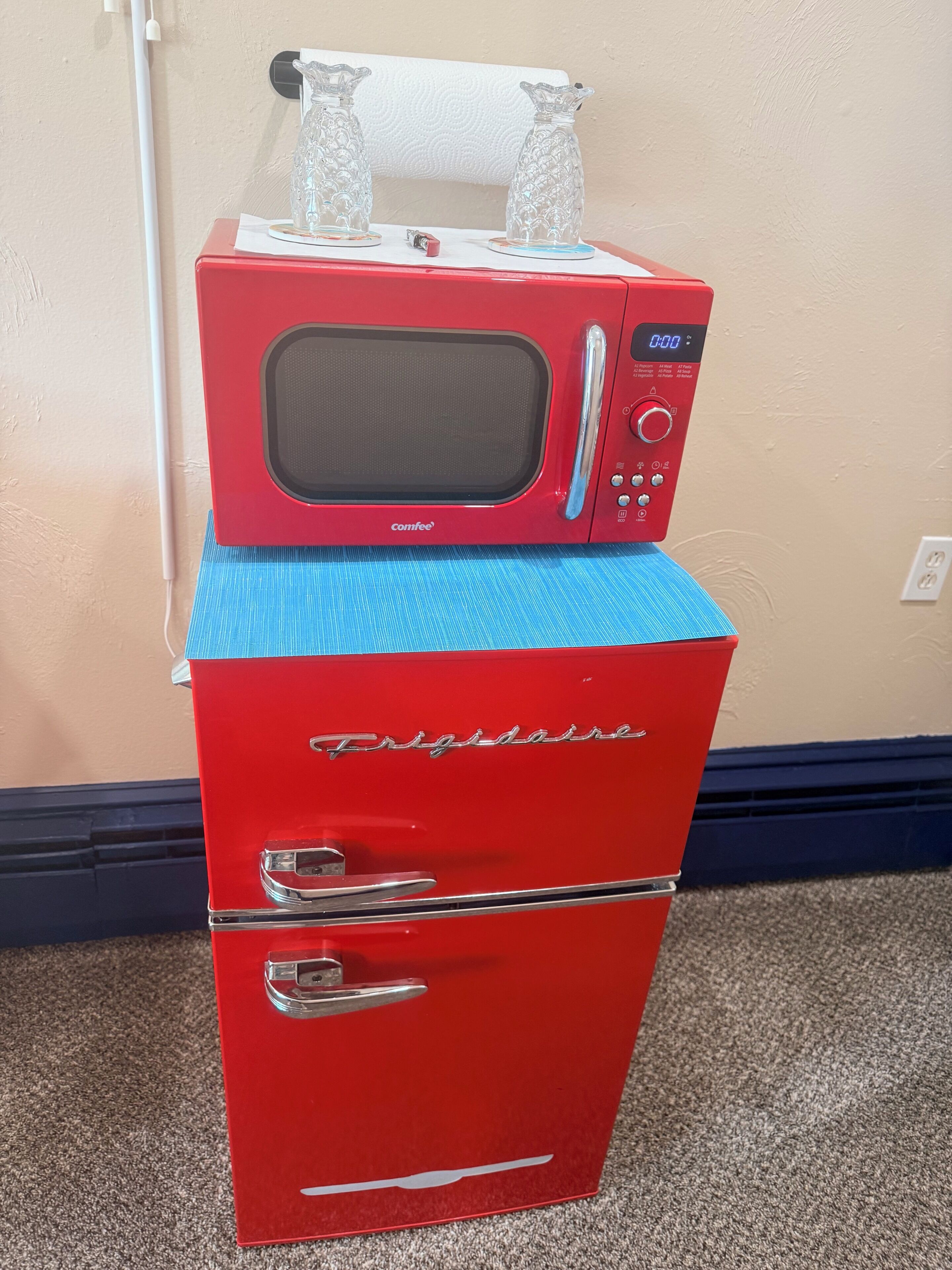Un microondas rojo Comfee encima de un refrigerador rojo Frigidaire.