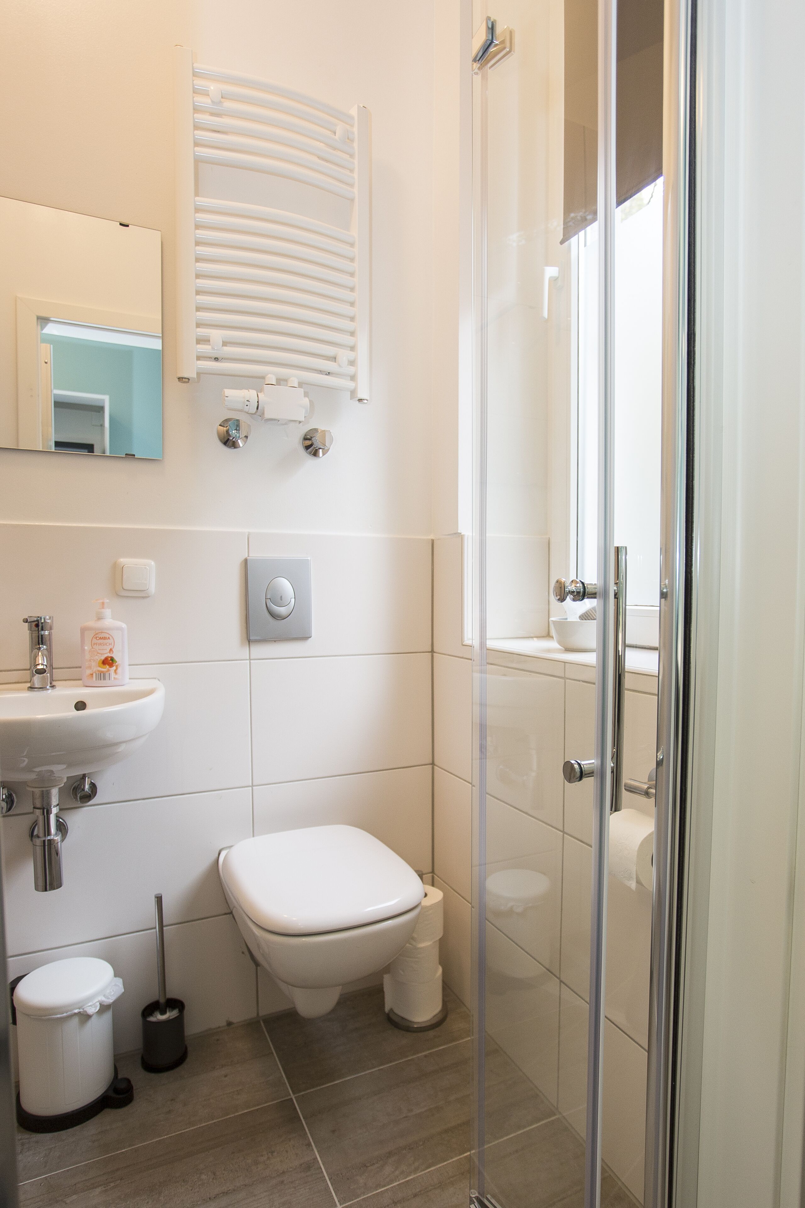 Un baño moderno con cabina de ducha de vidrio, un lavamanos blanco y un inodoro.