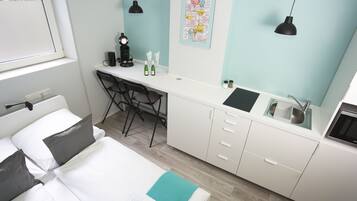 Et moderne hotelværelse med seng, skrivebord og tekøkken.