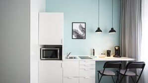 Une petite cuisine équipée comprenant un four à micro-ondes, un évier et deux chaises.