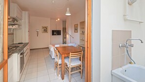 Een kleine keuken met een eethoek, een inbouwfornuis en een spoelbak.