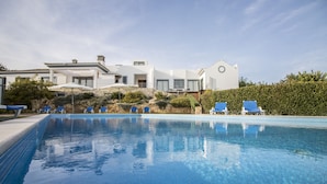 A swimming pool with lounge chairs, a white building with a modern design, and a well-maintained garden. - Casa Serena | 6 Bedrooms | Country House |  Estoi (Estoi)
