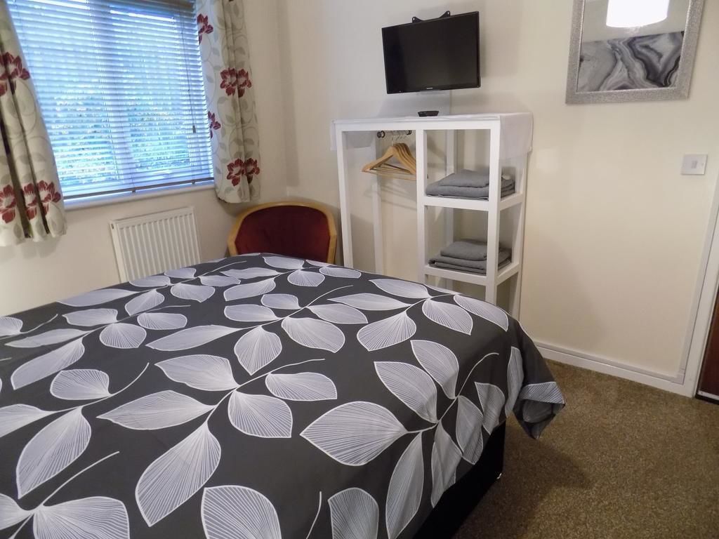 A bedroom with a bed, a TV on the wall, a wardrobe, and a chair.