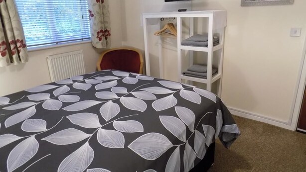 A bedroom with a bed, a TV on the wall, a wardrobe, and a chair. - A Home From Home 3 (Plymouth)