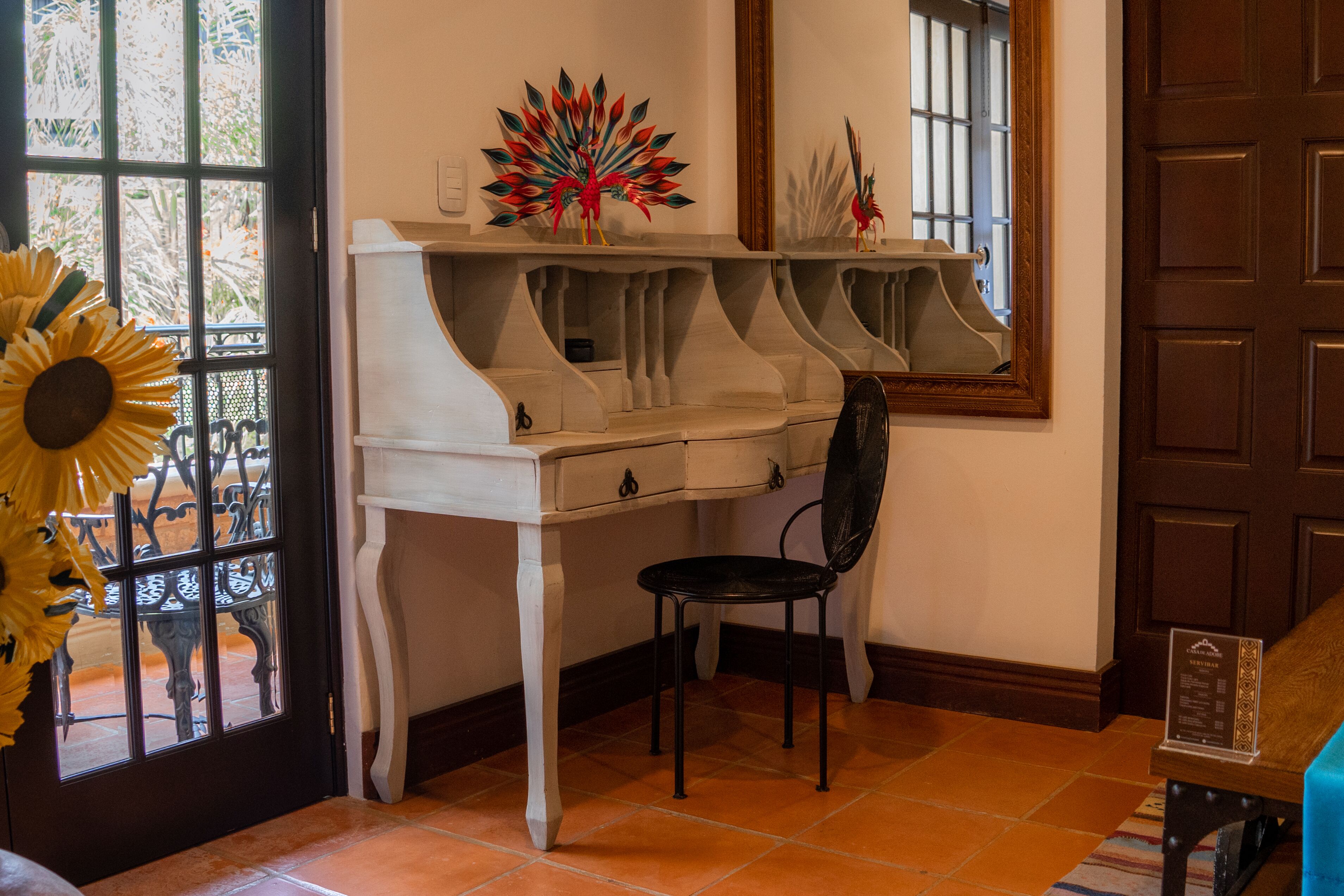 A room with a white piano, a black chair, and a decorative plant.