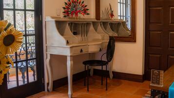 A room with a white piano, a black chair, and a decorative plant.