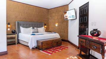 A bedroom with a brick wall, a bed with white linens, a wooden nightstand, a red and yellow rug, and a wooden dresser with drawers.