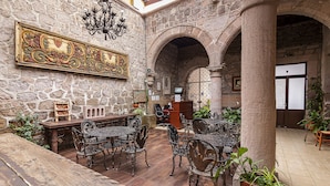 A stone-walled courtyard with outdoor seating, a chandelier, and a large decorative painting. - Hotel Cantera Rosa (Morelia)