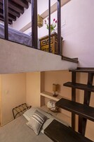 Una habitación pequeña y acogedora con una cama nido, una mesita con una lámpara y un estante con adornos.