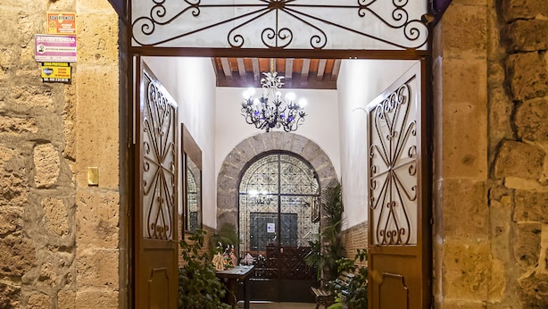 The entrance to Hotel Cartera Rosa with a wrought iron gate and a chandelier above. - Hotel Cantera Rosa (Morelia)