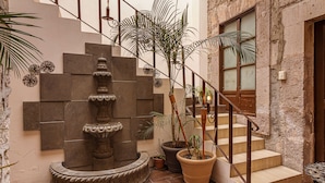 A staircase with a fountain, potted plants, and a rustic wall. - Hotel Cantera Rosa (Morelia)