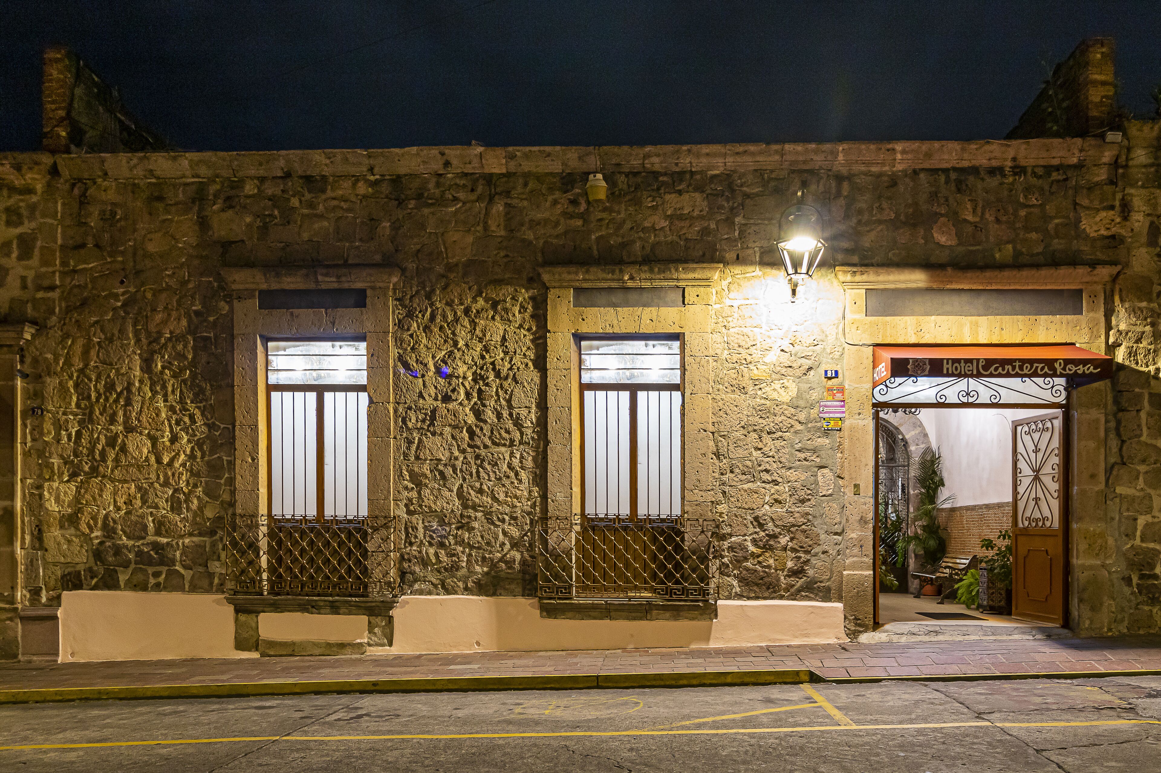A stone building with two windows, a door, and a small bench.