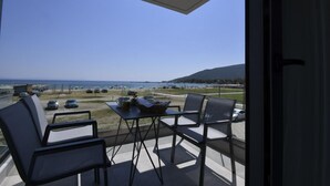 A balcony with a table and chairs, overlooking a beach and parking area. - Alos Utopia (Volvi)