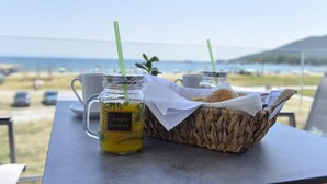 A table with a mug, a glass with a straw, and a basket with bread. - Alos Utopia (Volvi)