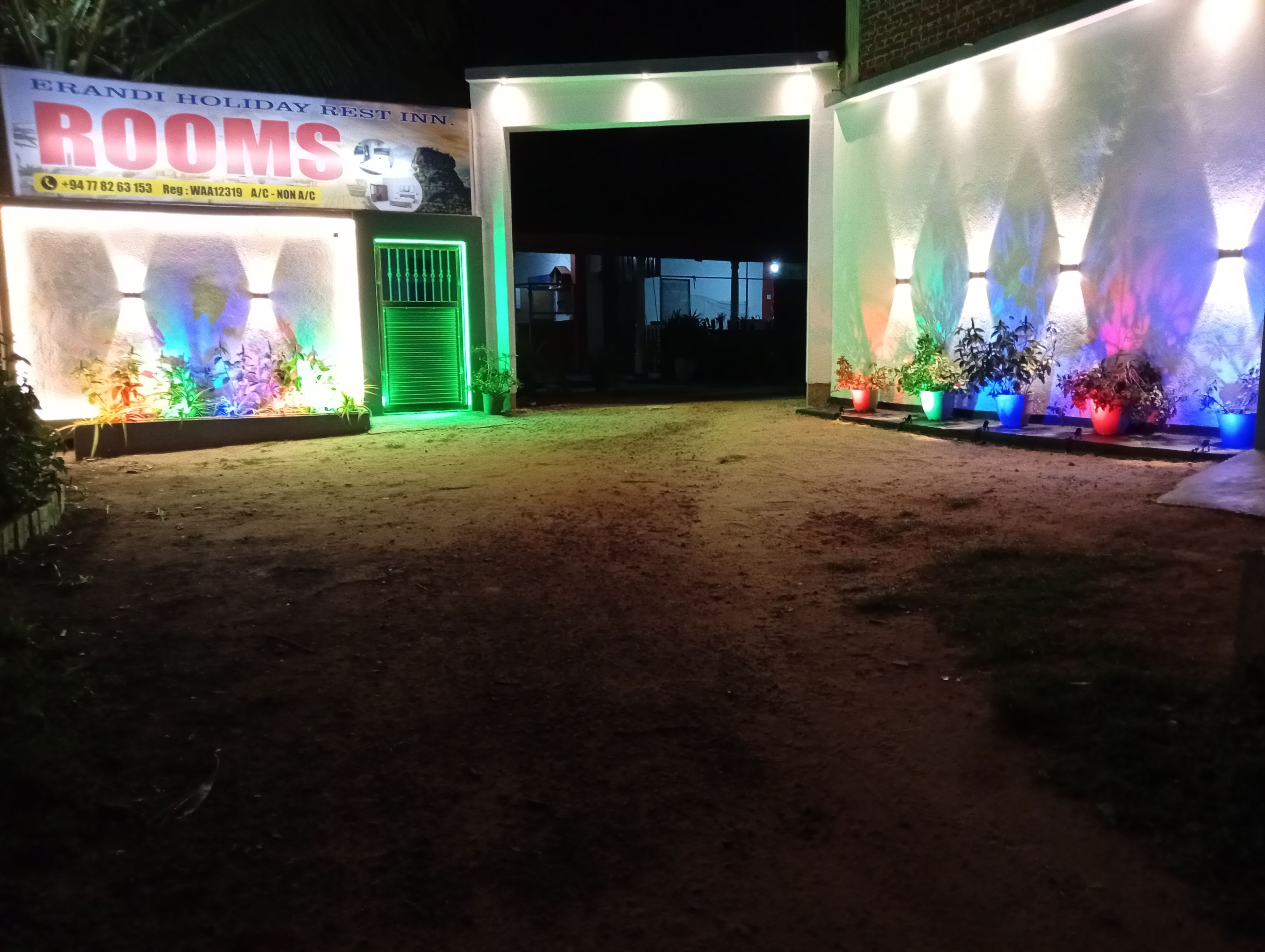 A hotel entrance with illuminated signage and potted plants.