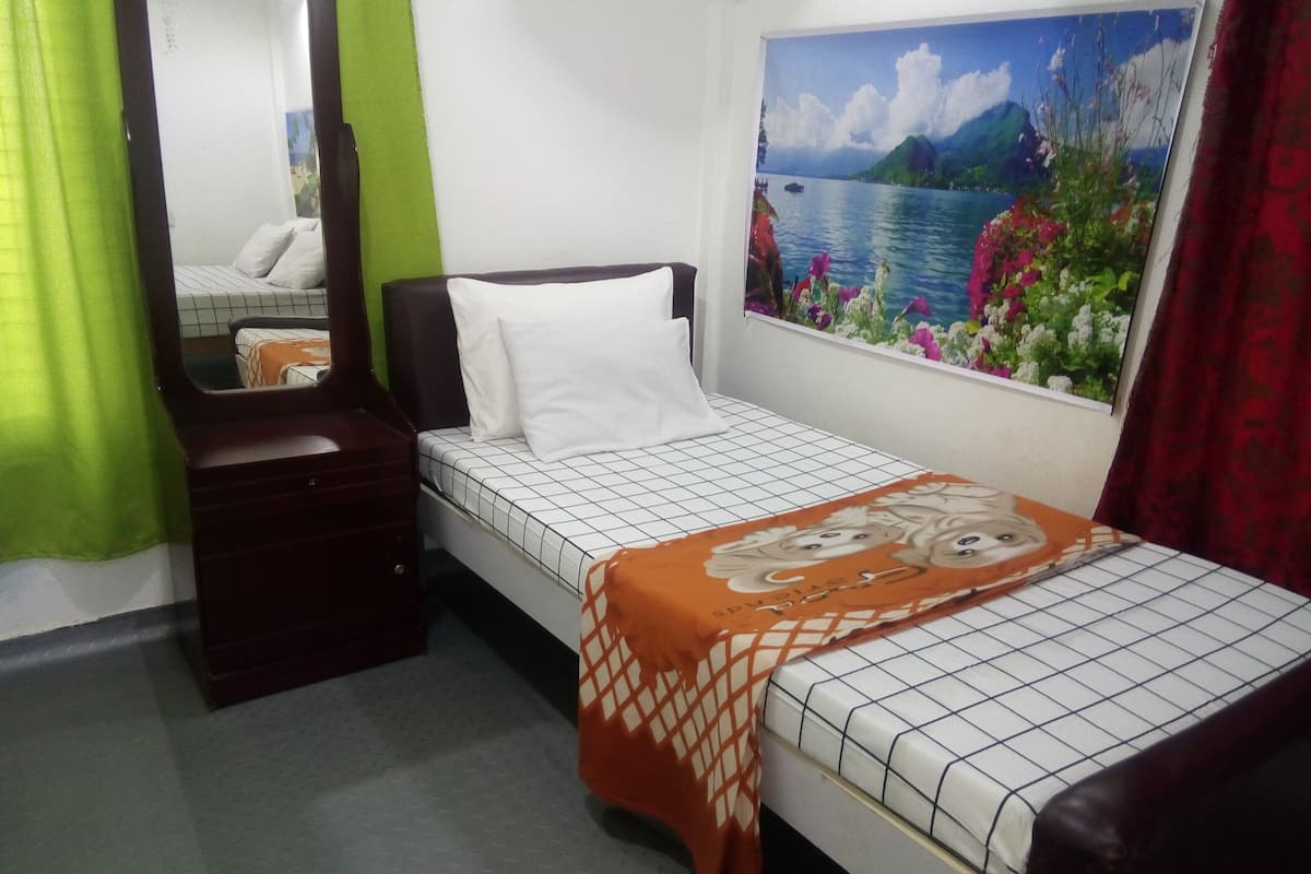 Une chambre à coucher comprenant un lit, une commode, un miroir et un tableau représentant un paysage.