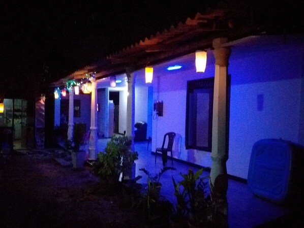 A building with a tiled roof and multiple windows. There are plants and outdoor furniture visible. - Erandi Holiday Home (Seeduwa - Katunayake)