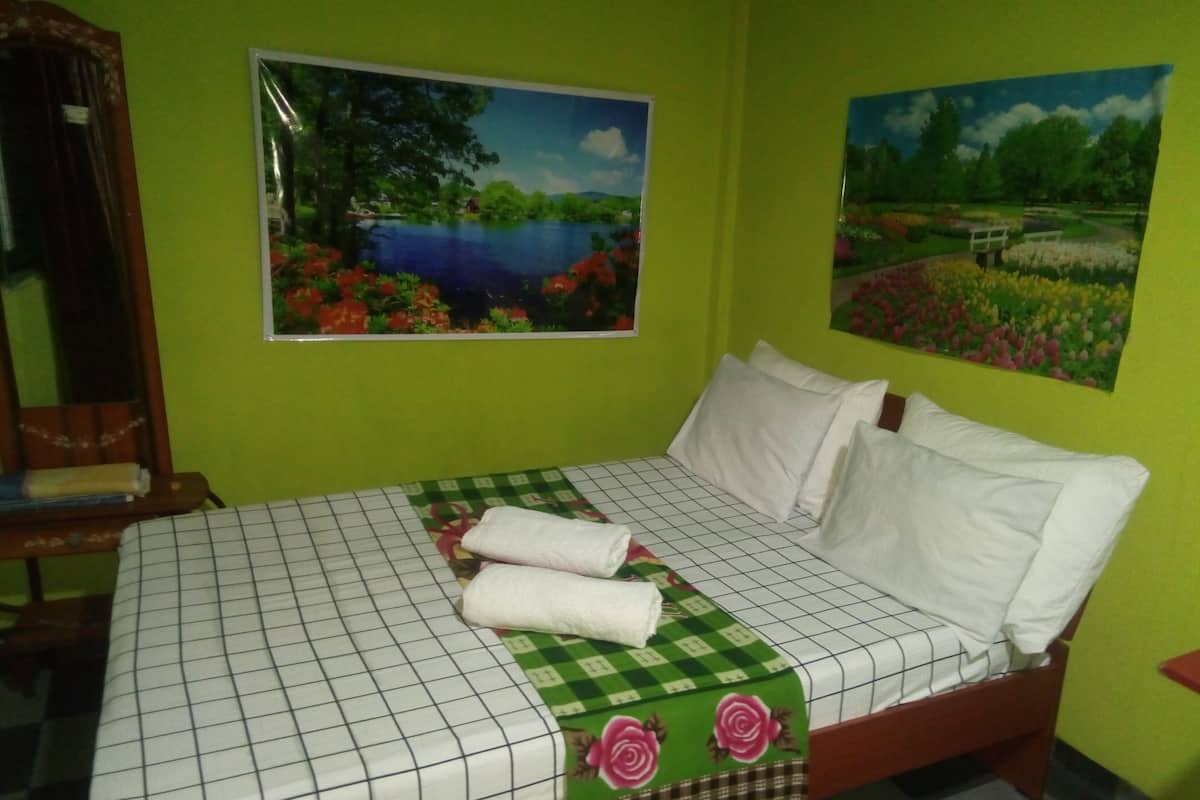 Une chambre à coucher avec un lit, des murs verts et deux tableaux représentant des paysages.
