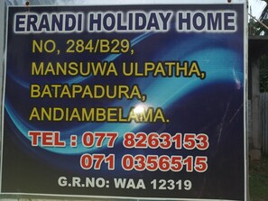 A sign for Erandi Holiday Home with contact details and address. - Erandi Holiday Home (Seeduwa - Katunayake)