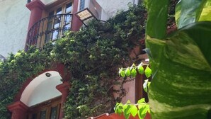 Ein Gebäude mit roten und weißen Wänden, einem Balkon mit roter Markise und Pflanzen an der Außenfassade.