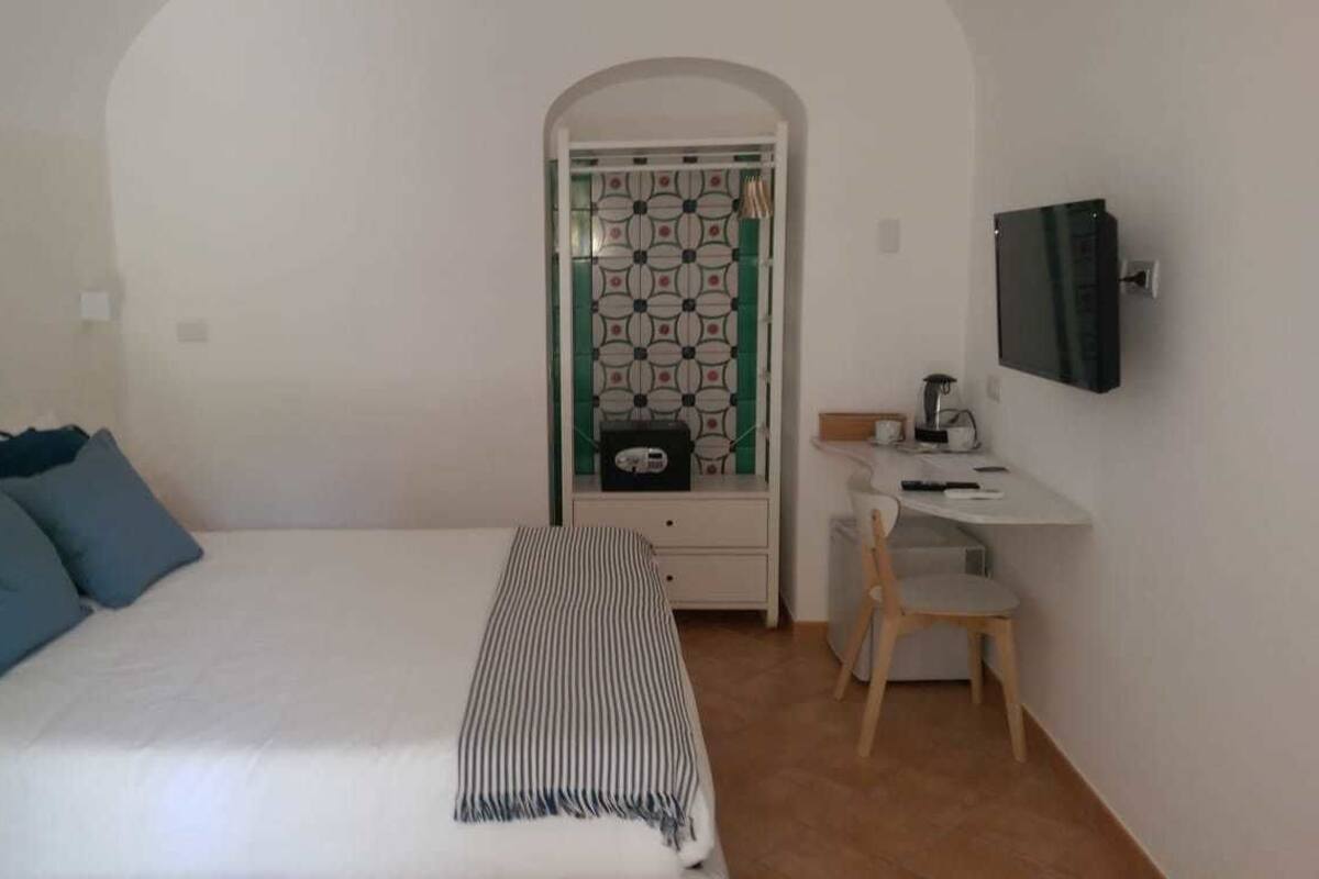 A bedroom with a bed, a desk, and a television.