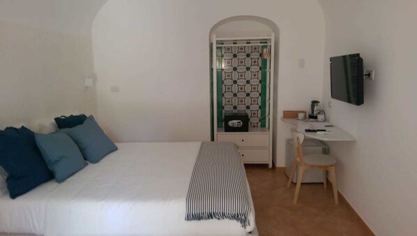 A bedroom with a bed, a desk, and a television. - Casa Amorino (Minori)