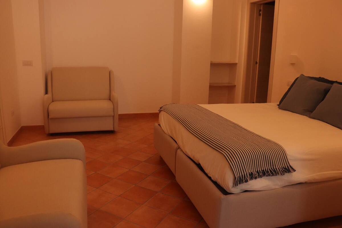 A bedroom with a bed, a chair, and a small table.
