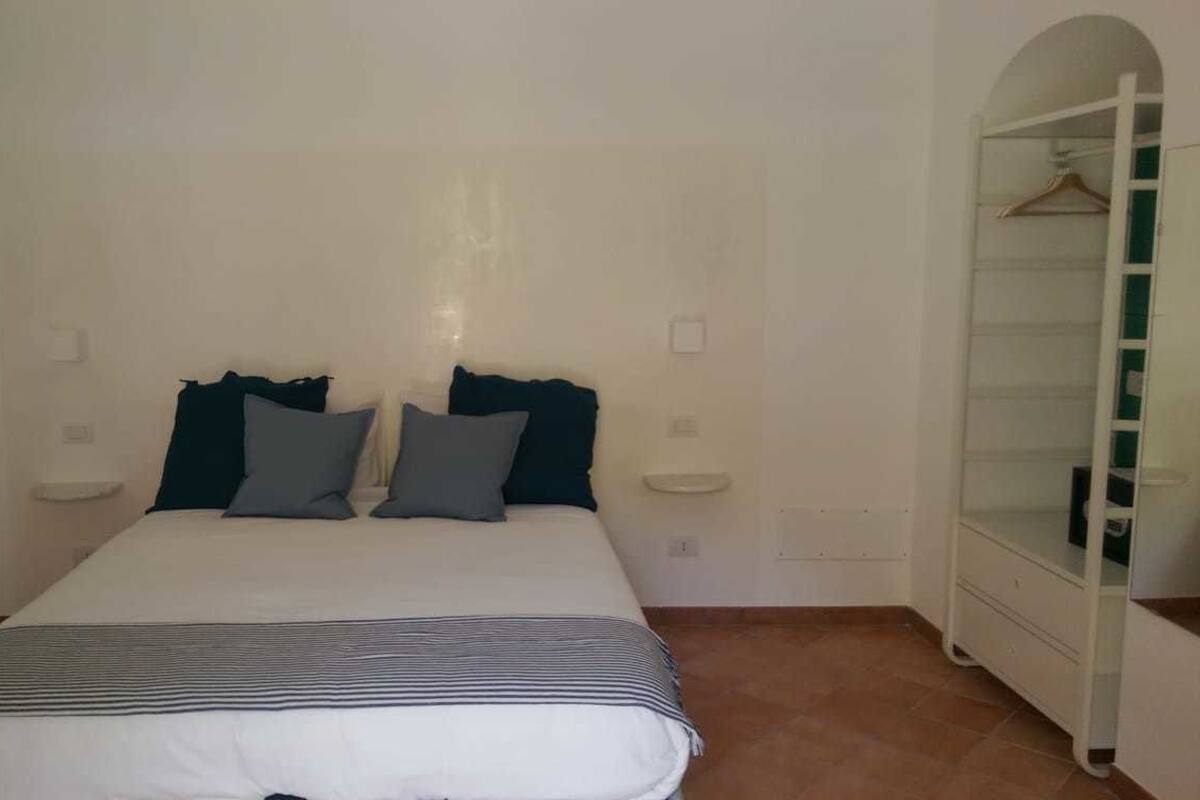 A bedroom with a bed, pillows, a bedside table, and a wardrobe.
