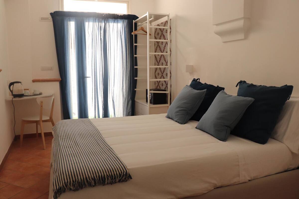 A bedroom with a bed, bedside table, chair, and a wardrobe.