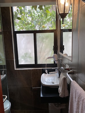 A bathroom with a sink, mirror, and window.