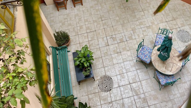 An outdoor patio area with tiled flooring, multiple seating arrangements, and various potted plants. - Quinto Sol 2 Departamento (San Miguel de Allende)