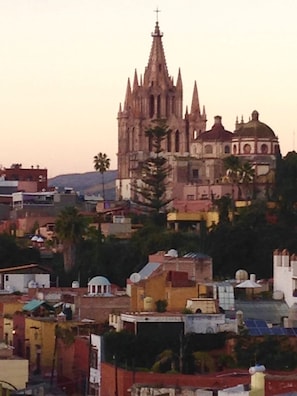 Una catedral con una aguja alta y una cúpula, rodeada de edificios residenciales y palmeras.