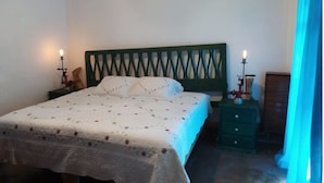 A bedroom with a bed, nightstands, a dresser, and a window with curtains. - Quinto Sol 4 Departamento (San Miguel de Allende)