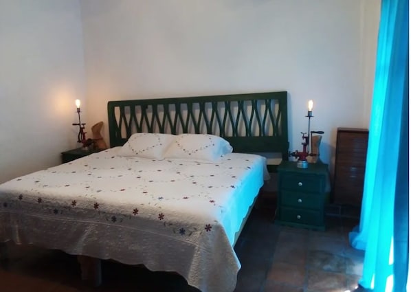 A bedroom with a bed, nightstands, a dresser, and a window with curtains.