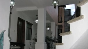 A staircase with a handrail, a tiled floor, and a ceiling with hanging light fixtures. - Quinto Sol 4 Departamento (San Miguel de Allende)