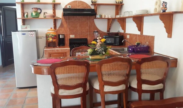A kitchen with a dining table, chairs, a refrigerator, a stove, and a microwave.