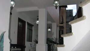 Una escalera con barandilla, piso de baldosas y techo con lámparas colgantes.