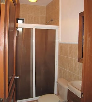 A bathroom with a toilet, a shower enclosure, and a sink.