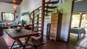 A cozy room with a wooden dining table, a sofa, and a staircase leading to an upper level. - Pipa Casa Cândido (Tibau do Sul)
