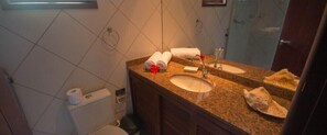 A bathroom with a double sink, a mirror, and a toilet.