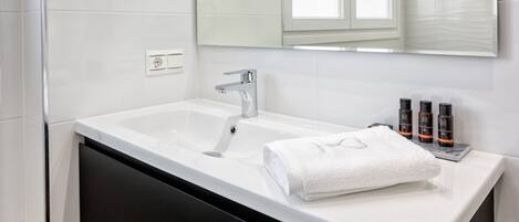 Ein modernes Badezimmer mit einem weißen Waschbecken, einem schwarzen Schrank und einem großen Spiegel darüber.
