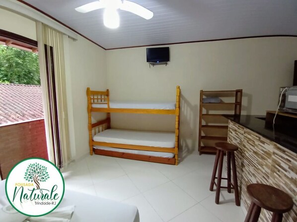 A room with a bunk bed, a TV mounted on the wall, and a wooden bar counter with stools. - Pousada Naturale (Paraty)