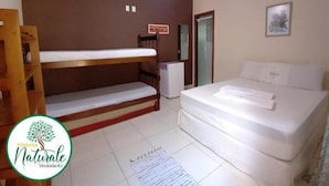 A room with a bunk bed, a single bed, a ceiling fan, a small refrigerator, and a door leading to a bathroom. - Pousada Naturale (Paraty)