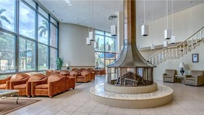 Un hall d’entrée spacieux avec une cheminée centrale, des sièges confortables et un escalier.