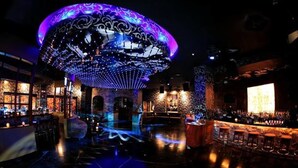 Un espace bar doté d’une grande structure en forme de dôme illuminé, de tabourets de bar et d’une scène avec un grand écran.