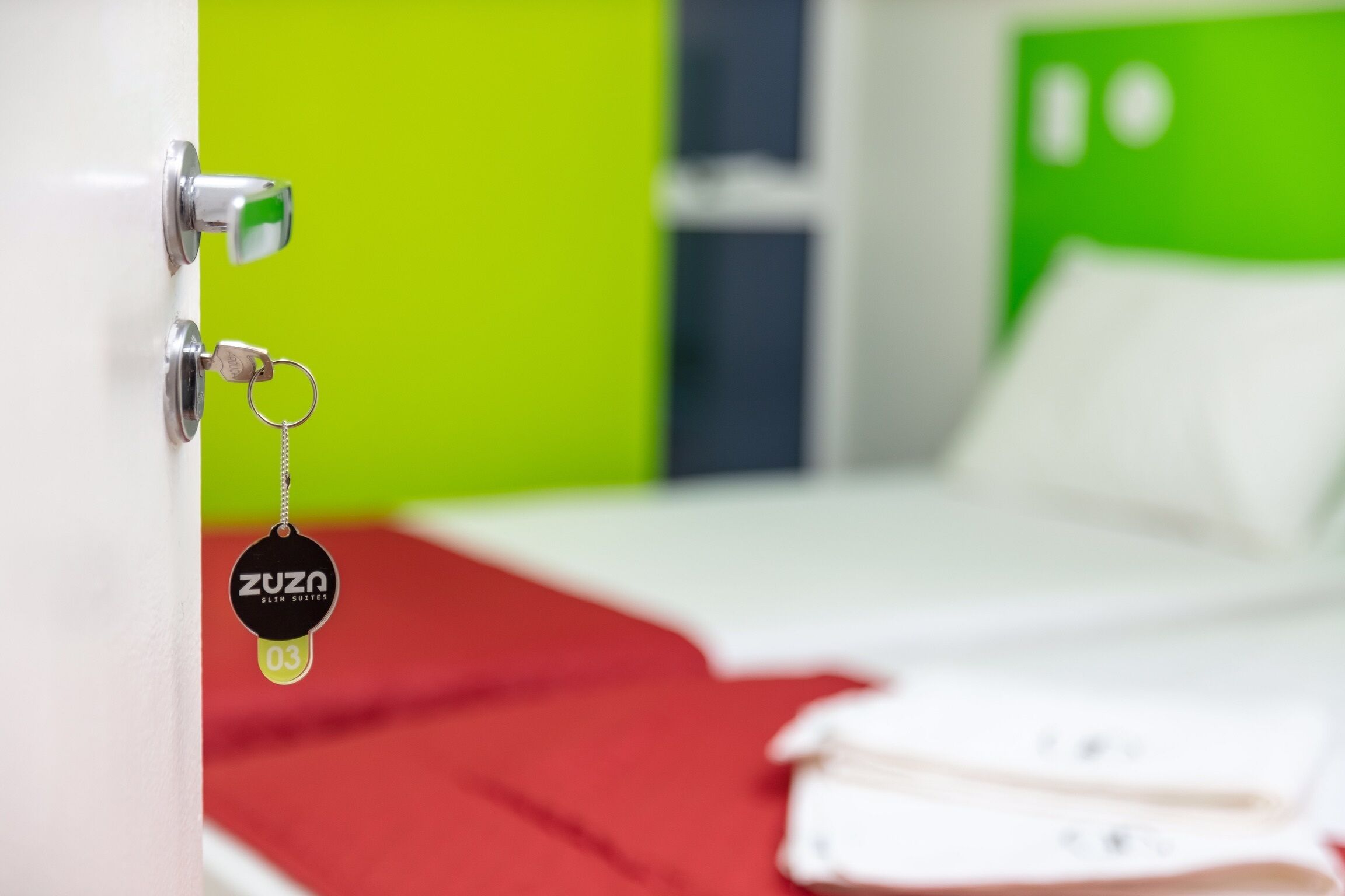 Una habitación de hotel con una cama, una colcha roja y un llavero con etiqueta.