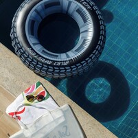 A poolside area with a tire, a towel, and sunglasses.